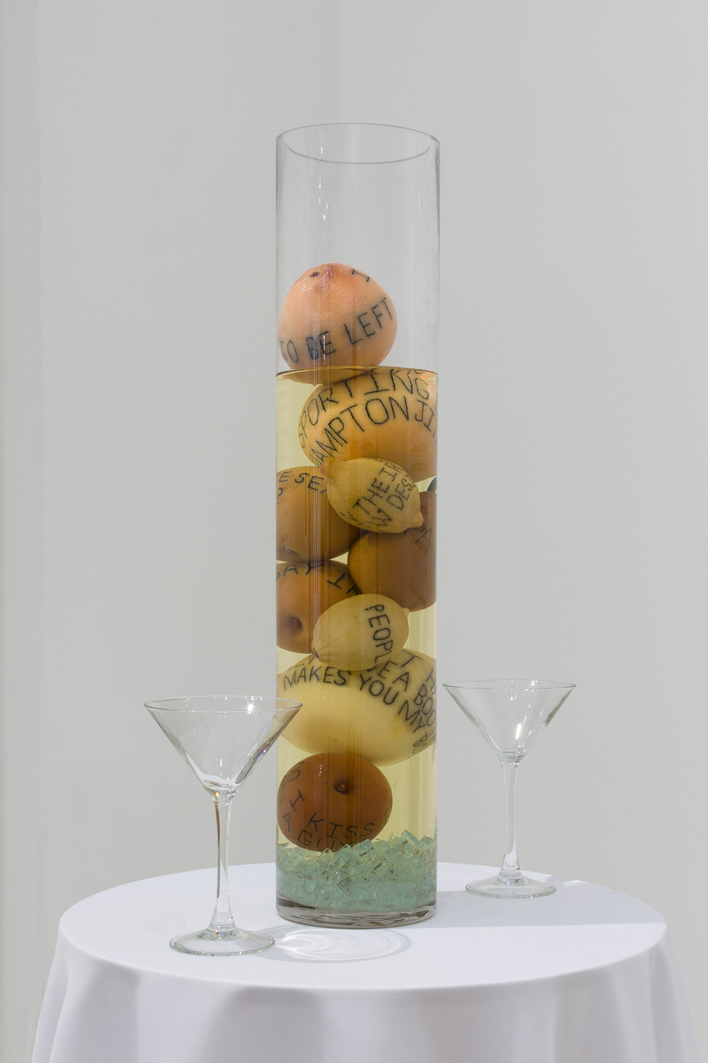 Detail of a round table top with a column filled with tattood fruit and alcohol on it